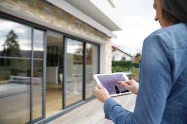 Frau bedient mit Smart Home System Terrassentür